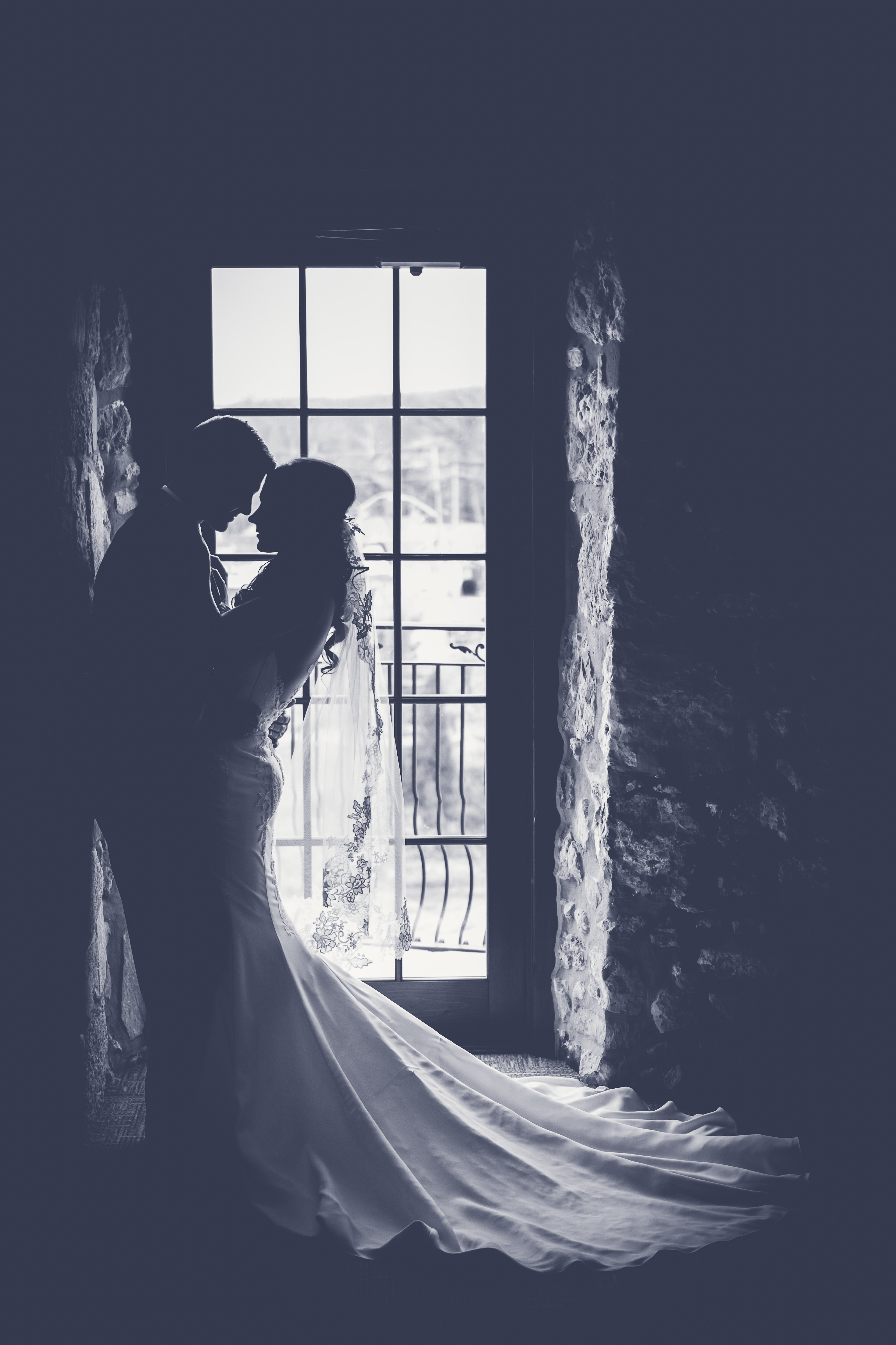 A wedding couple embracing by a window
